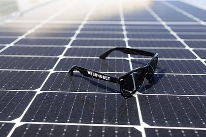 Solglasögon med Webbhuset-logotyp placerade på solpaneler, en symbol för företagets fokus på hållbara e-handelslösningar och grön digital utveckling.