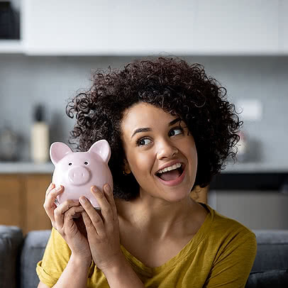 A happy woman holding a pink piggy bank