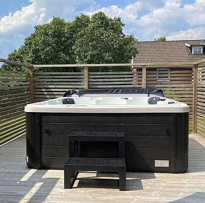 A black jacuzzi from Outl1 stands on a terrace in the sunlight