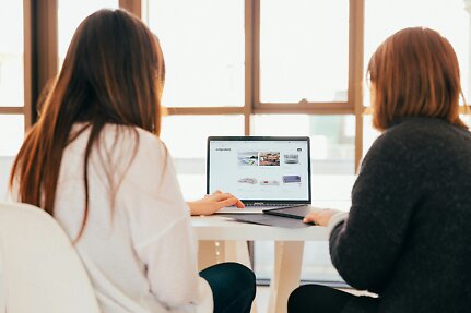 Två kollegor som granskar en e-handelssida på en laptop hos en webbyrå i Göteborg.