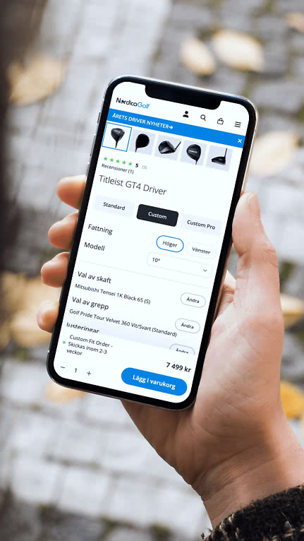 En person håller i en smartphone som visar NordicaGolfs produktsida med en produktkonfigurator för en golfklubba.