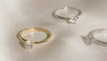 En guldring och två silverringar av Vanbruun på en vit silkesduk