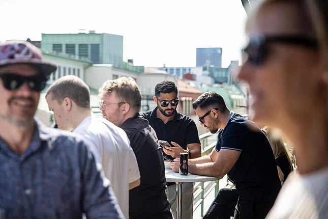 Grill party at Webbhuset, employees sit on the balcony enjoying the sun at the office in central Gothenburg.