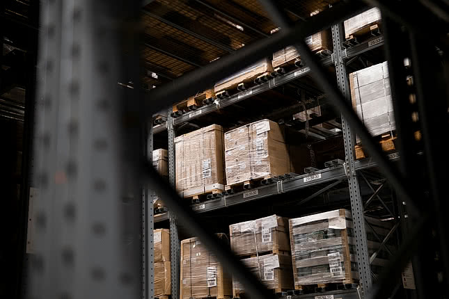 Bild på ett lager med staplade lastpallar, som symboliserar logistik och effektivitet för B2B e-handel.